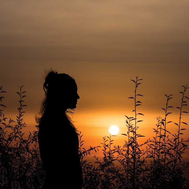 Woman sitting alone at sunset